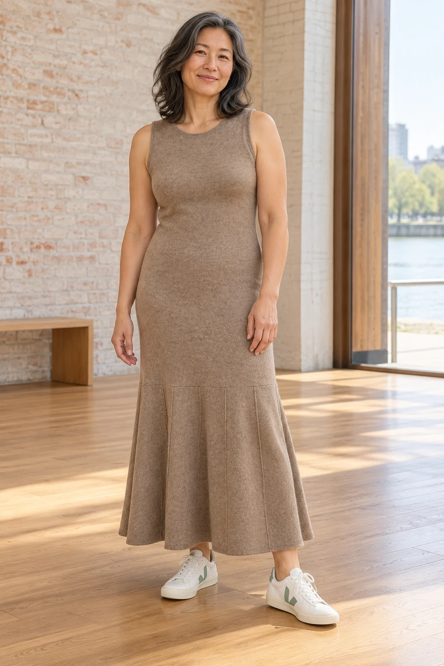 An adult woman wears a long bark Ruohan knit dress with white and pale green Veja trainers in Toronto.