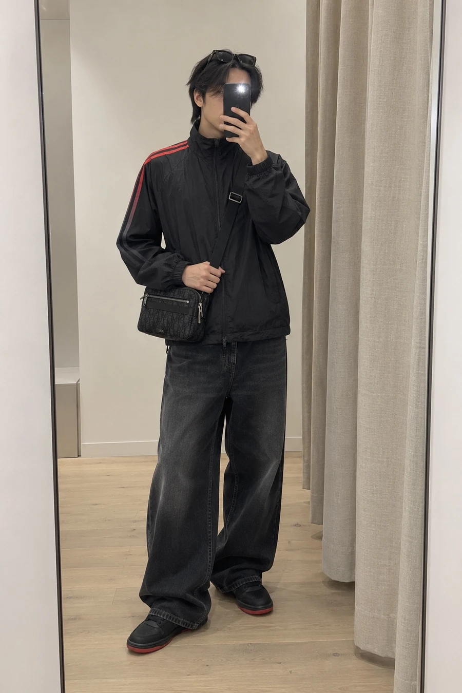 A Taiwanese man photographs his reflection in a fitting room mirror in a Y-3 track top, Walk in Paris baggy jeans, Nike SB Dunks and a Dior bag.