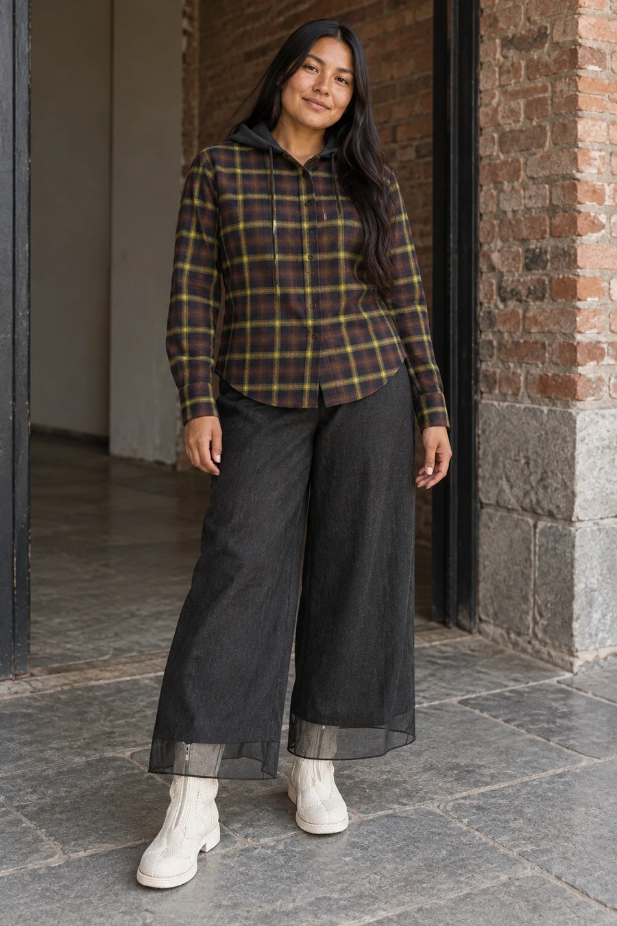 An adult woman wears a brown Coperni plaid shirt with an attached hood, black Ruohan trousers and white piped Guidi boots in Toronto.