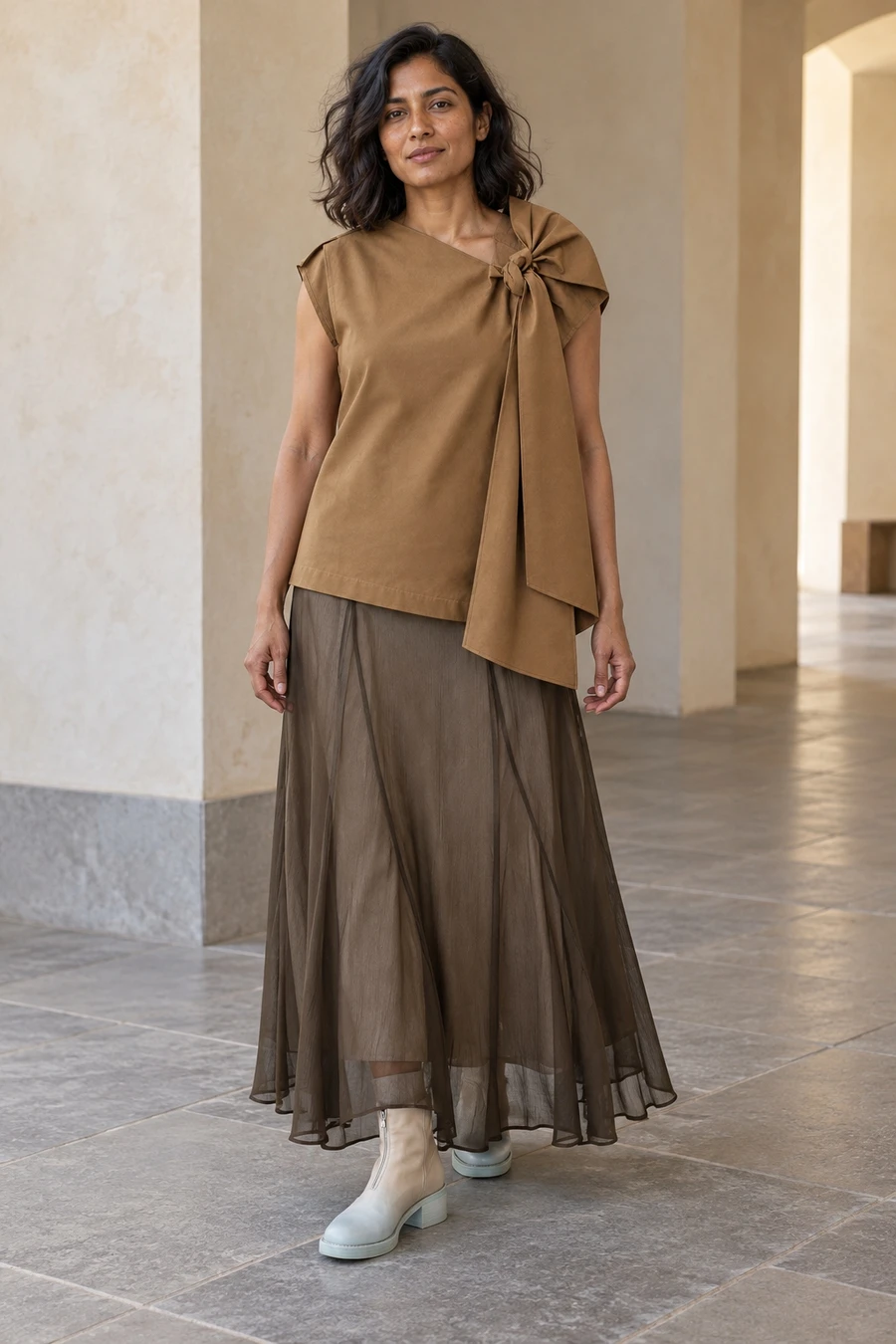 An adult woman wears a brown Ujoh shoulder tied blouse with a willow Ruohan skirt and beige to aqua Guidi boots in London.