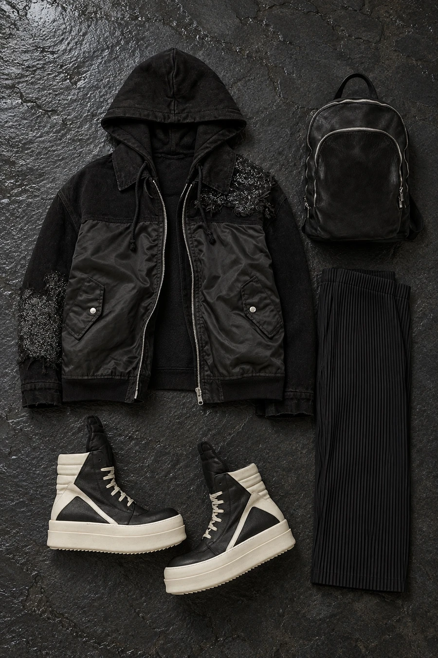 Flat lay of a black Song for the Mute jacket, black Issey Miyake trousers and black and milk Rick Owens sneakers.