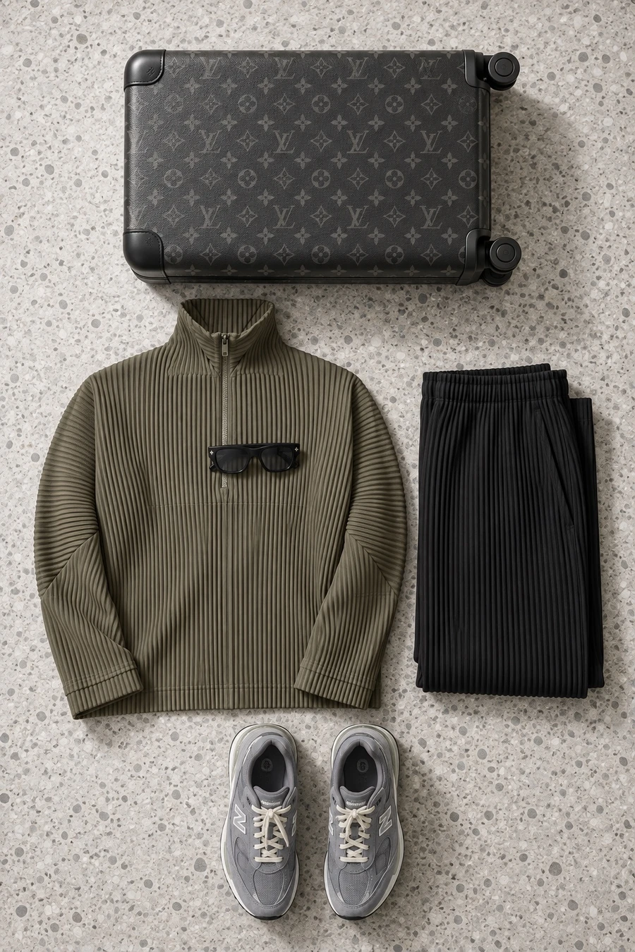 An early flight out of Haneda. Flat lay of an olive Issey Miyake quarter zip, black trousers and grey New Balance sneakers.
