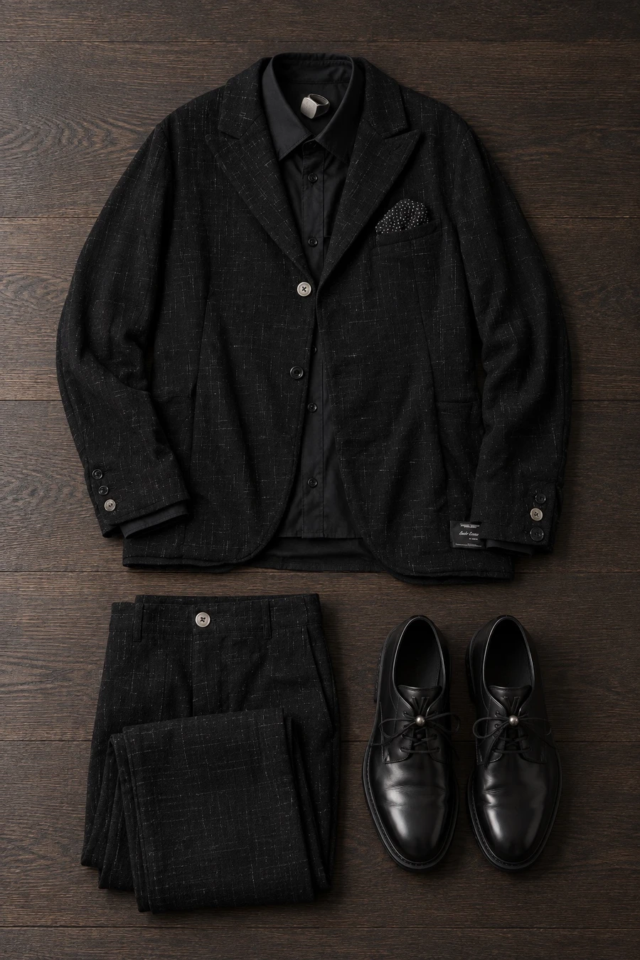 An evening wedding in October. Flat lay of a black Undercover jacket, black trousers, a black Balenciaga shirt and black Louis Vuitton derbies.