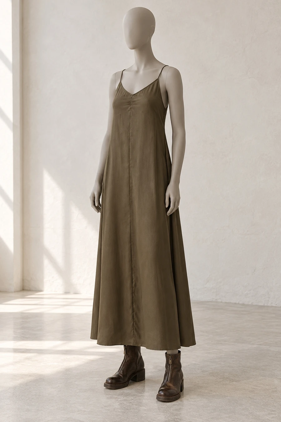 A faceless display mannequin in a New York showroom. An olive brown RUOHAN slip dress meets dark brown Guidi ankle boots.
