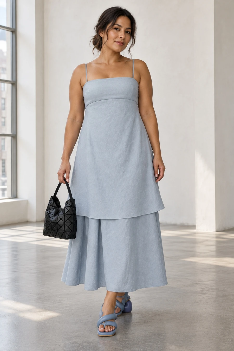 An adult woman wears a powder blue RUOHAN dress and blue Yume Yume heels, holding a small black Bao Bao handbag in a New York gallery entrance.