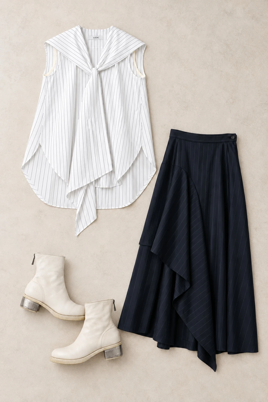 A flatlay of a white striped UJOH sailor collar top, navy asymmetric skirt and a pair of white Guidi boots with metal heels.