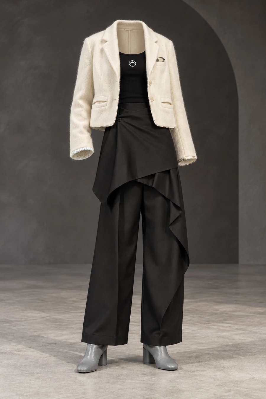 Ivory Undercover jacket over a black tank and black wrap trousers, with grey block heel ankle boots in a charcoal studio.